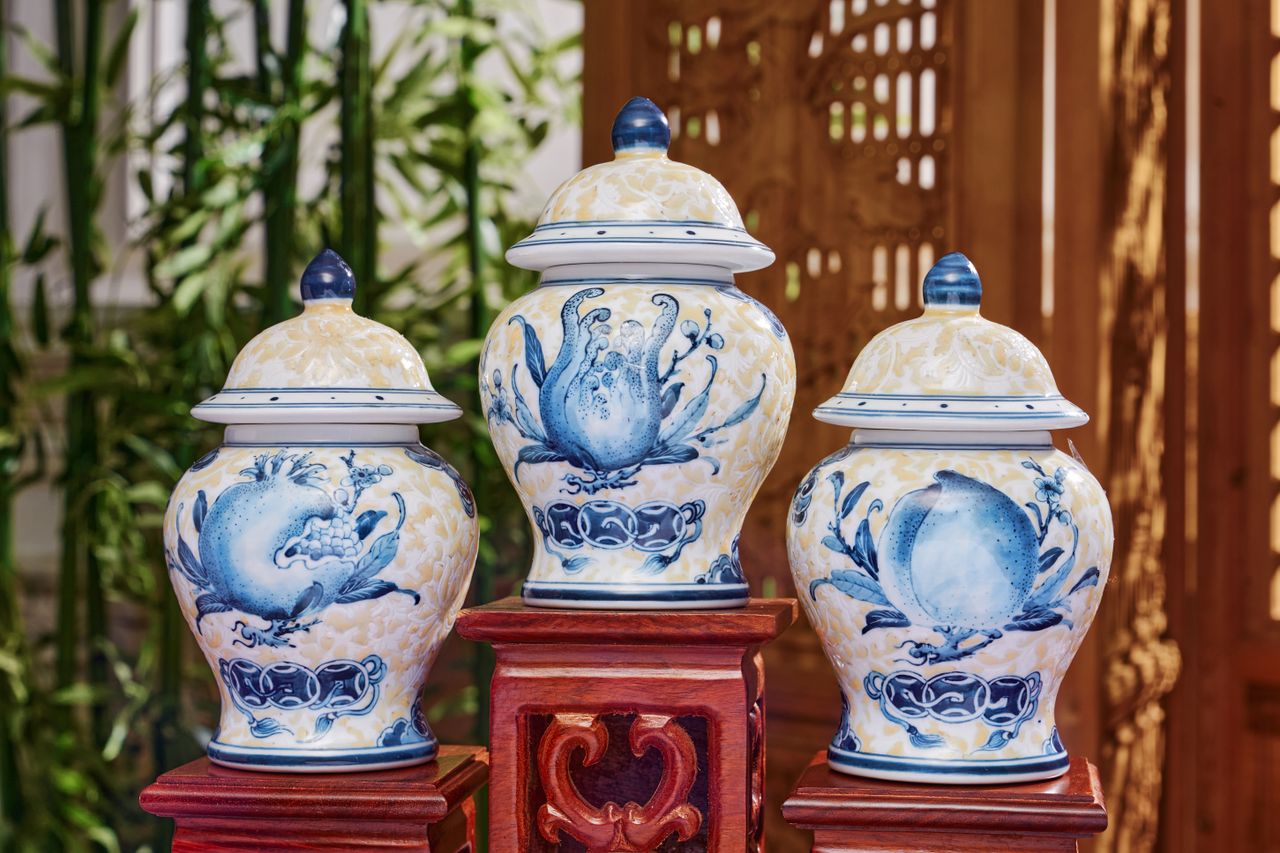 Three blue and white ceramic vases elegantly displayed with intricate designs, set against a wooden backdrop.