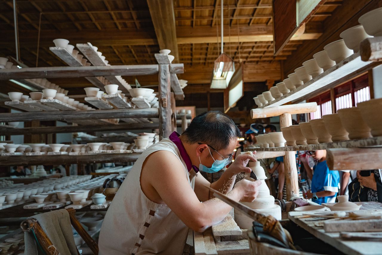 Artisan focused on pottery making in a traditional workshop, showcasing craftsmanship and artistry.